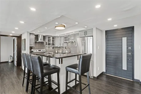 a kitchen with stainless steel appliances kitchen island granite countertop a dining table chairs and wooden floor