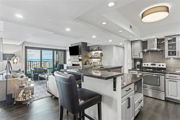 a kitchen with stainless steel appliances granite countertop a stove top oven a sink dishwasher a dining table and chairs with wooden floor