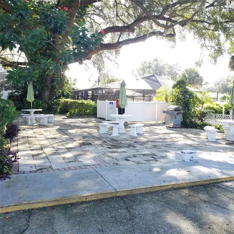 a view of a white house next to a yard with large trees