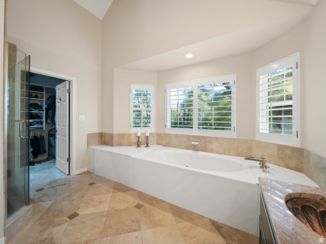 13357 Trail Rider Circle Draper, UT 84020 - Photo 28 of 70 Deep soaking tub with surrounding stone tile, plantation shutters, vaulted ceiling, glass-enclosed shower, and stone tile flooring