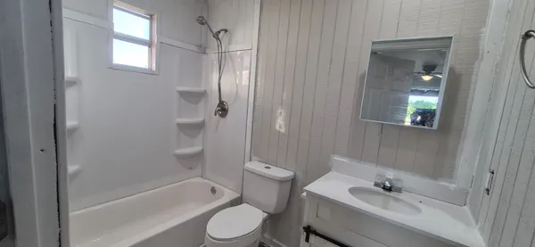 a bathroom with a bathtub shower sink vanity and toilet