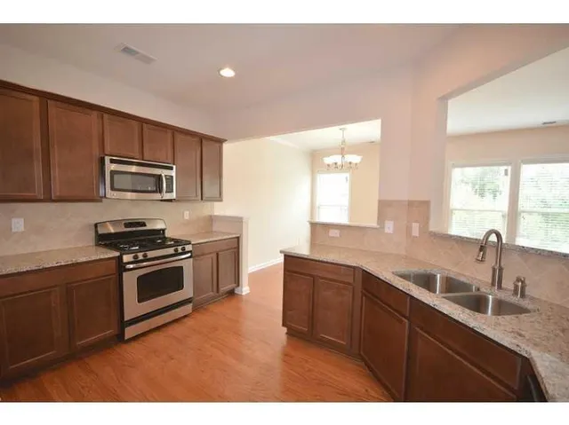 a kitchen with stainless steel appliances granite countertop a sink stove and microwave