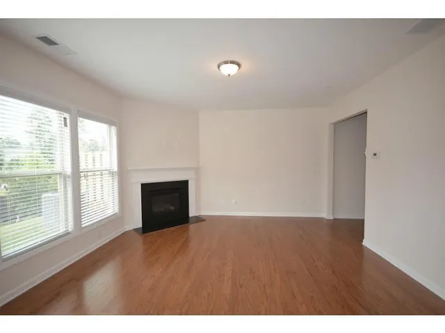 a view of an empty room with a window and wooden floor