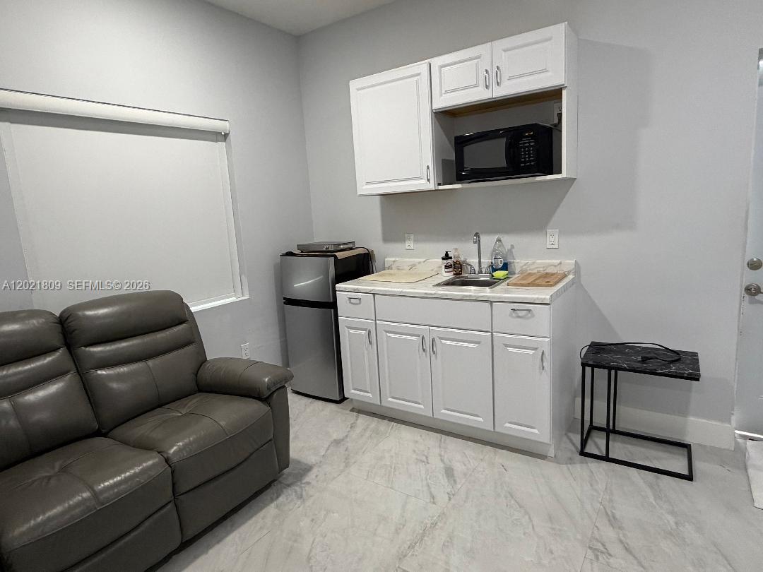 6803 Southwest 158th Avenue Miami, FL 33193 - Photo 3 of 6 a living room with a couch and a microwave
