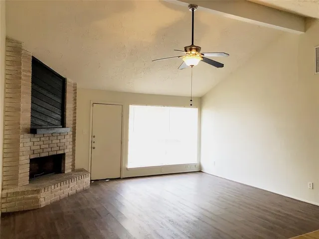 a view of a livingroom with a fireplace a ceiling fan and wooden floor
