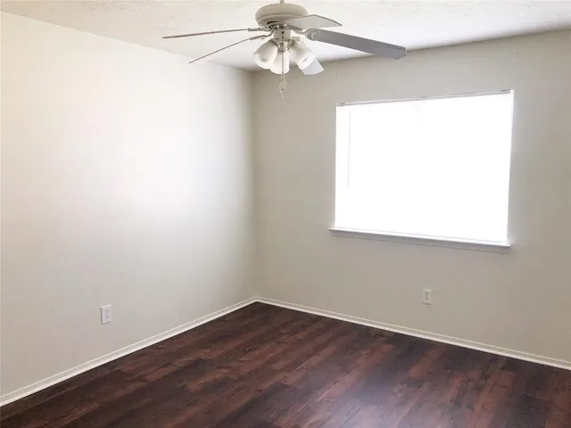 an empty room with wooden floor chandelier fan and window