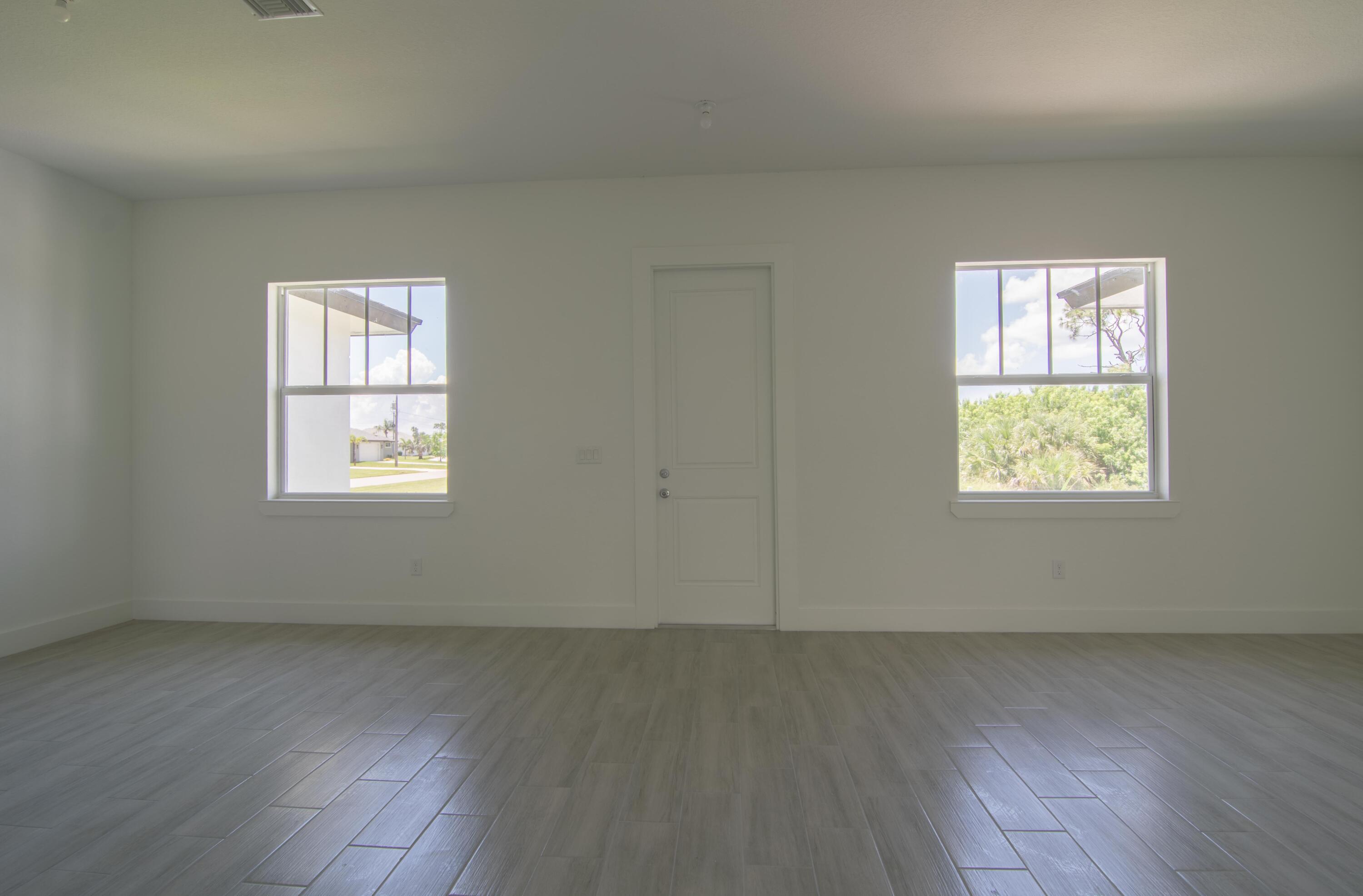 10654 Washington Road Port Charlotte, FL 33981 - Photo 12 of 36 an empty room with wooden floor and windows