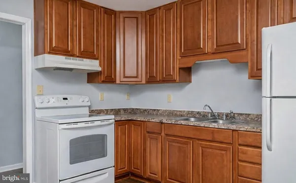 a kitchen with granite countertop wooden cabinets stainless steel appliances and a sink
