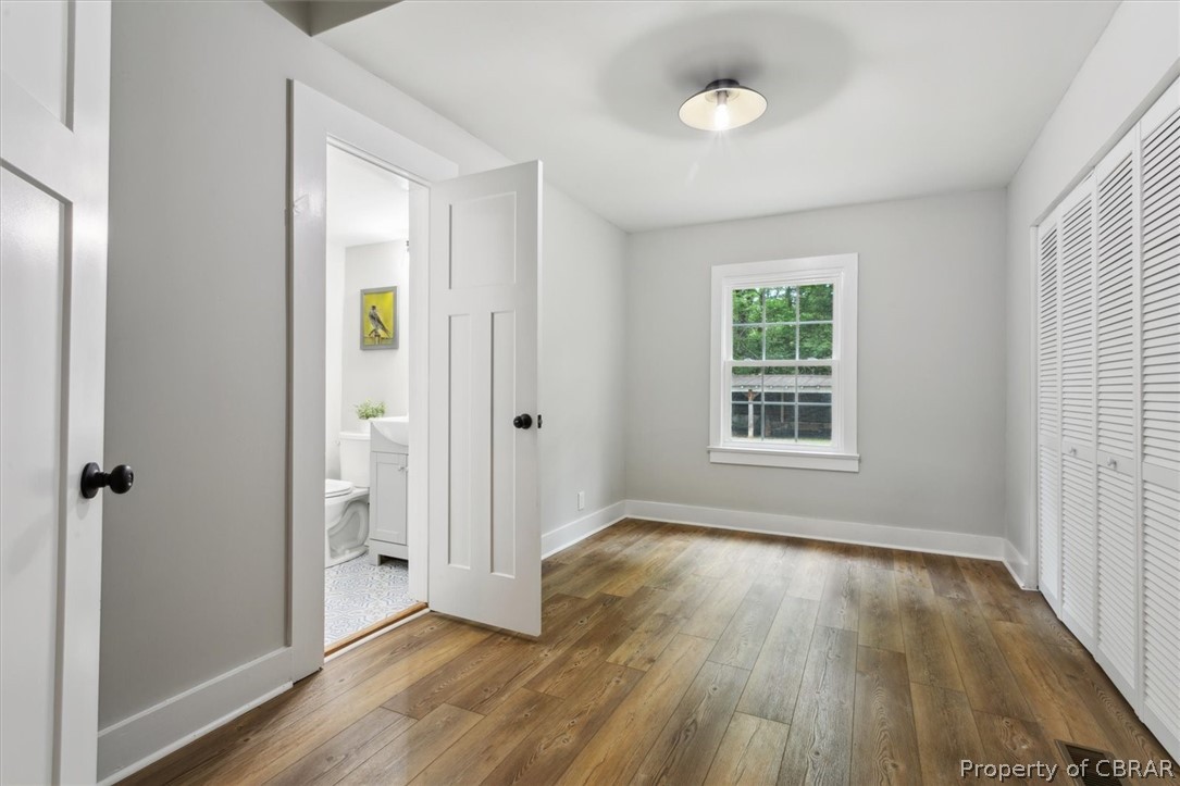 8213 Croaker Road Williamsburg, VA 23188 - Photo 23 of 50 Unfurnished bedroom with ensuite bath, dark hardwood / wood-style flooring, and a closet
