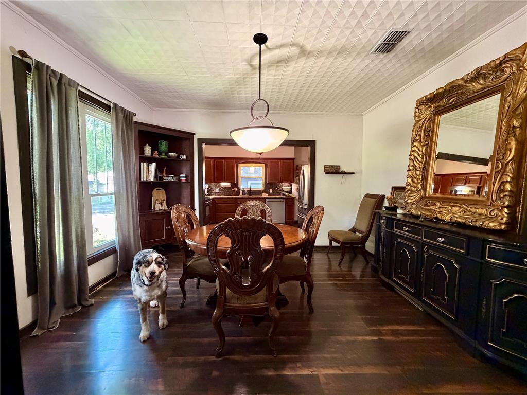 301 Forrest Avenue Cleburne, TX 76033 - Photo 10 of 14 Dining area featuring dark wood-finish flooring, a decorative patterned ceiling, and a built-in corner bookshelf