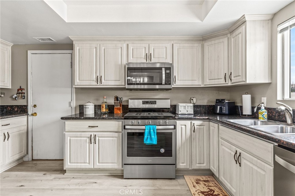 3998 Bluff Street Norco, CA 92860 - Photo 15 of 74 a kitchen with stainless steel appliances granite countertop a stove a sink and a white cabinets