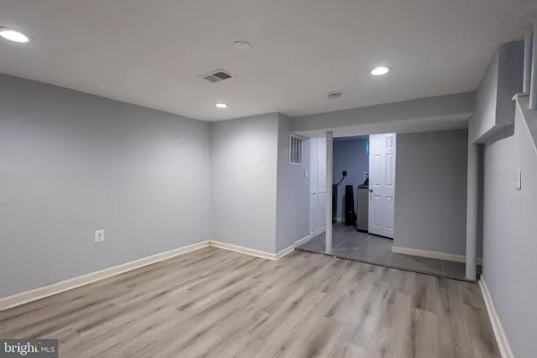 a view of an empty room with wooden floor and closet