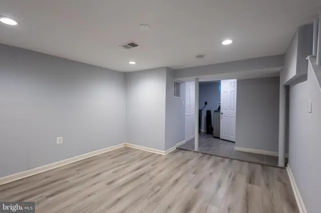 a view of an empty room with wooden floor and closet