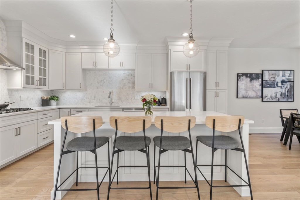 a kitchen with kitchen island granite countertop a dining table chairs and white cabinets