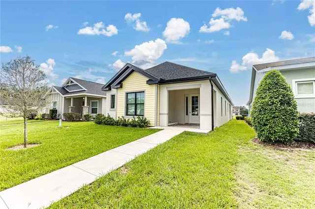 a view of a house with a big yard and large windows