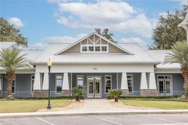 a front view of a building with a garden and trees