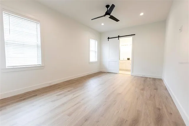 a view of empty room with wooden floor and fan
