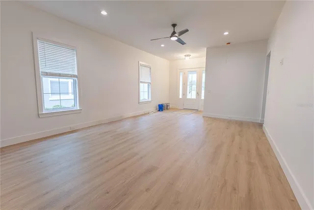 an empty room with wooden floor and windows