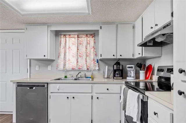 a kitchen with white cabinets and window