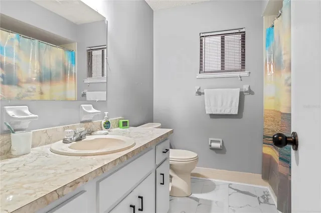 a bathroom with a granite countertop sink a toilet and a mirror