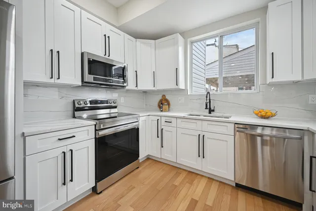a large kitchen with stainless steel appliances a refrigerator and a stove top oven