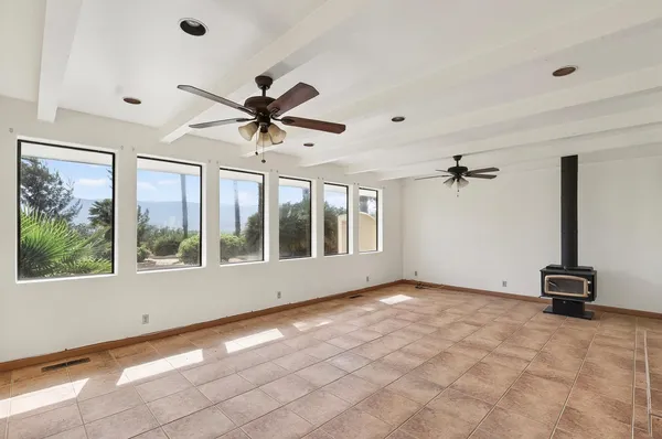 a view of a livingroom with a ceiling fan & kitchen furniture