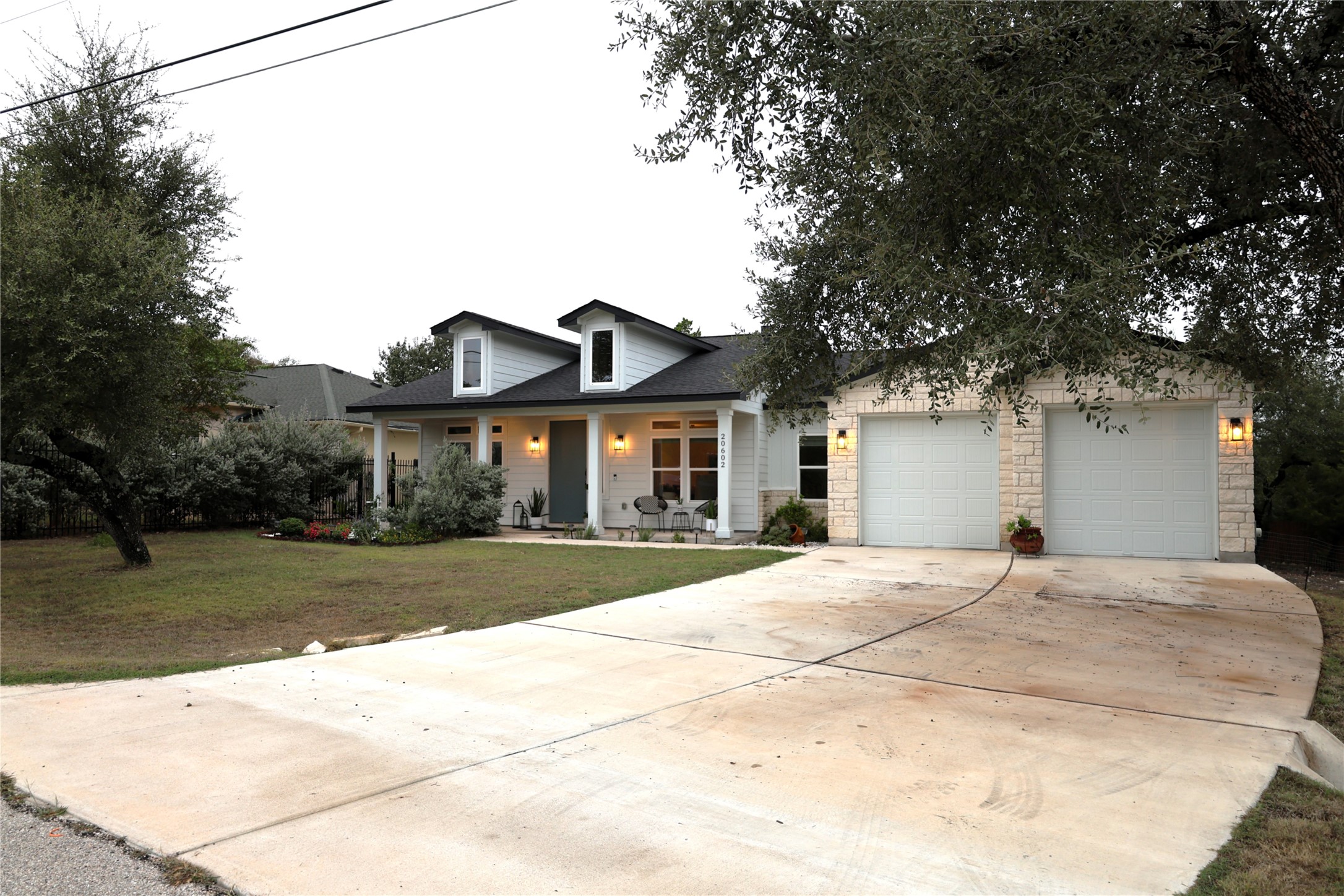 20602 Oak Ridge Lago Vista, TX 78645 - Photo 2 of 35 Mature trees frame a welcoming front elevation with stone accents and a wide concrete driveway.