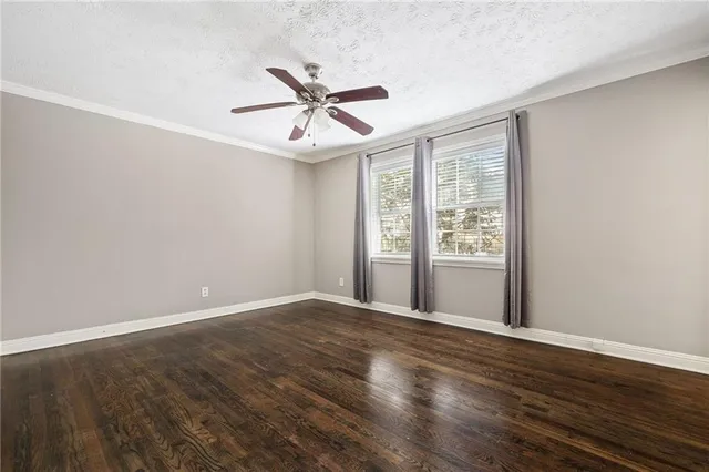an empty room with wooden floor fan and windows