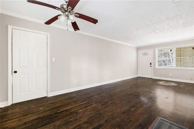 an empty room with wooden floor fan and windows