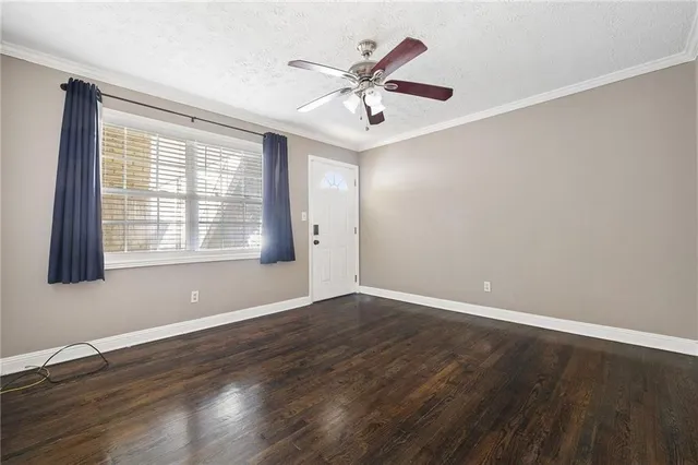 an empty room with wooden floor fan and windows