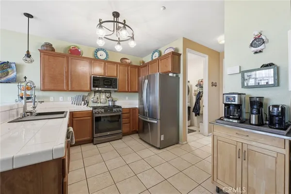 a kitchen view with stainless steel appliances kitchen island granite countertop a table chairs and a refrigerator