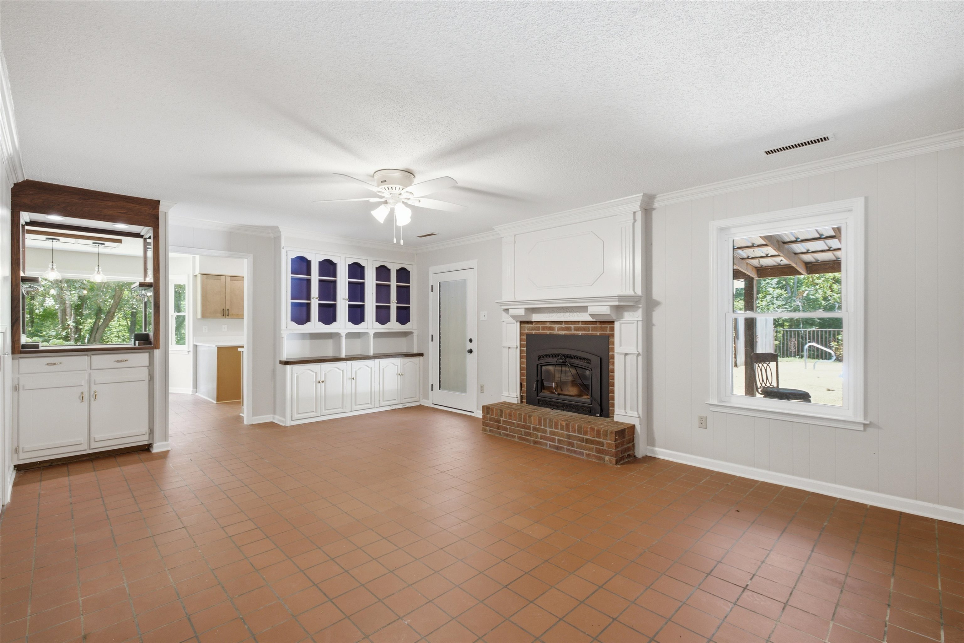 1370 North Reid Hooker Road Eads, TN 38028 - Photo 26 of 39 Spacious living area featuring terra cotta tile flooring, a brick fireplace with a white mantel, and built-in white cabinetry with open shelving