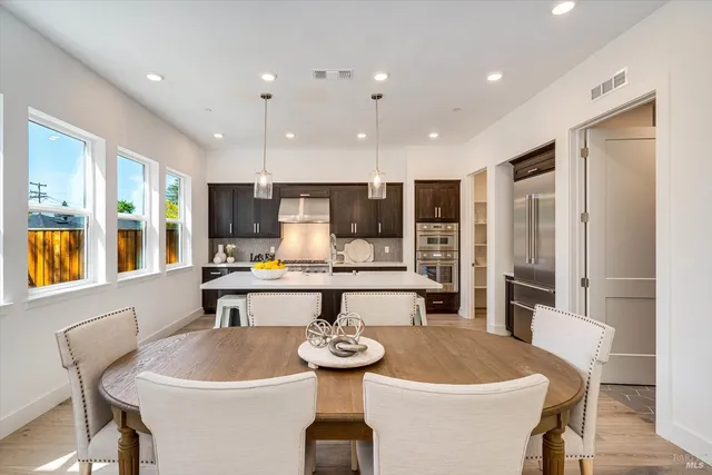 a large dining hall with stainless steel appliances kitchen island a table and chairs