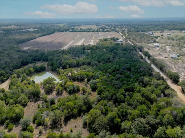 an aerial view of residential houses with outdoor space and trees