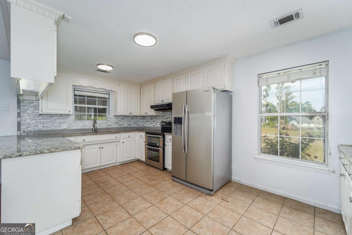 301 Ridge Lane Douglas, GA 31533 - Photo 11 of 26 a kitchen with granite countertop cabinets stainless steel appliances a sink and a window