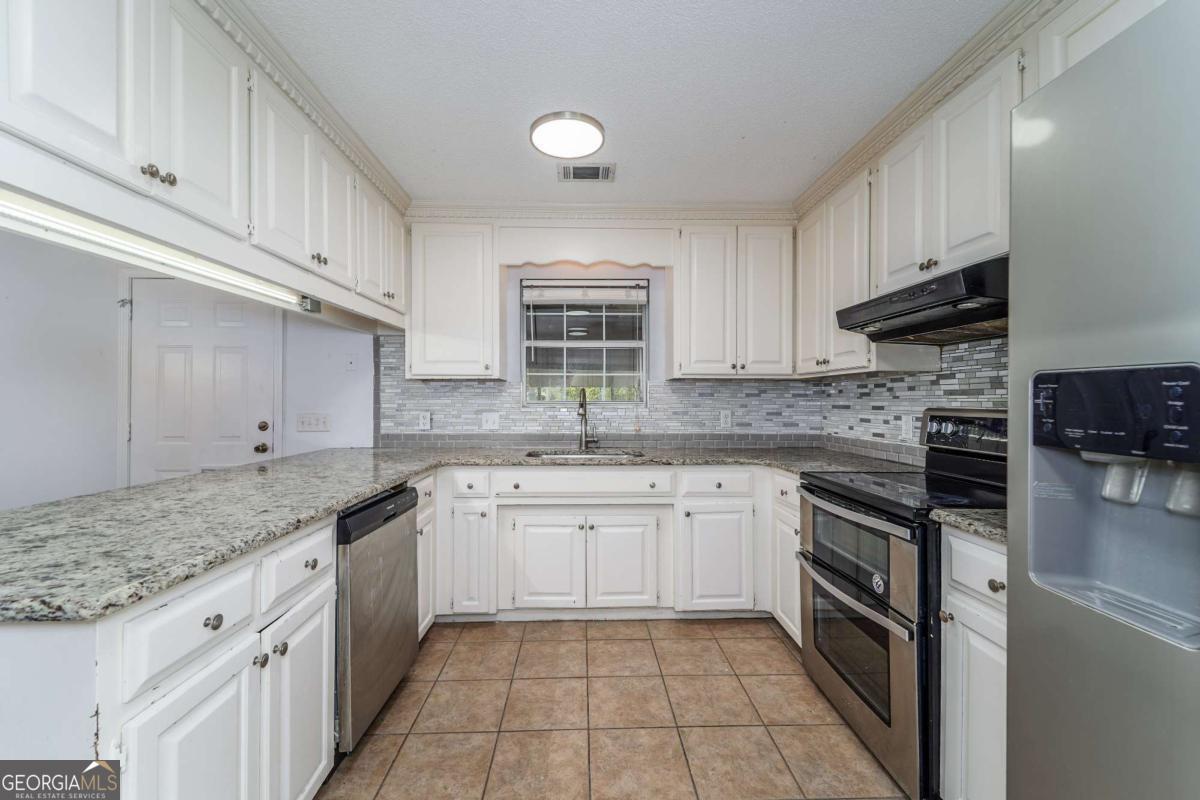 301 Ridge Lane Douglas, GA 31533 - Photo 12 of 26 a kitchen with stainless steel appliances granite countertop a sink stove and refrigerator