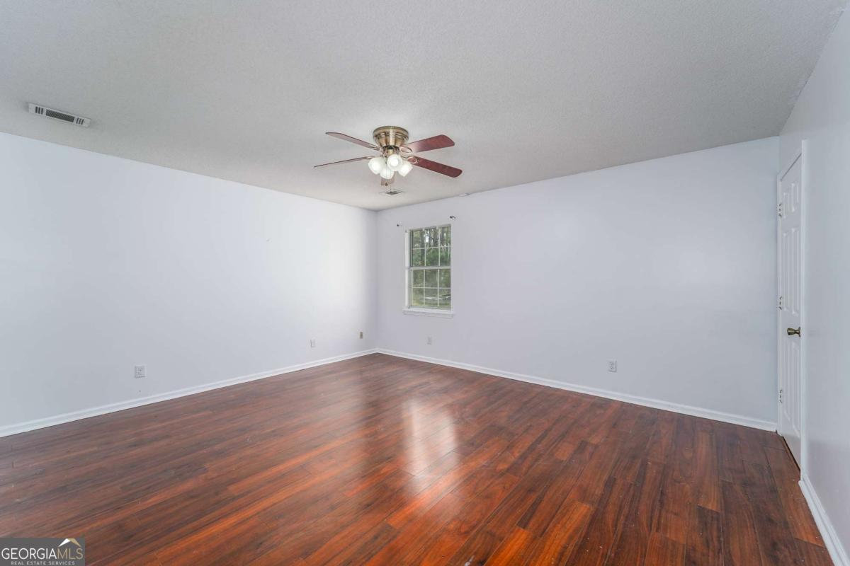 301 Ridge Lane Douglas, GA 31533 - Photo 21 of 26 a view of an empty room with a window and wooden floor