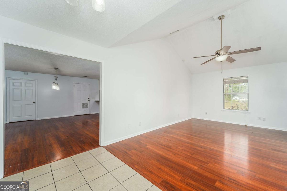 301 Ridge Lane Douglas, GA 31533 - Photo 7 of 26 an empty room with wooden floor fan and windows