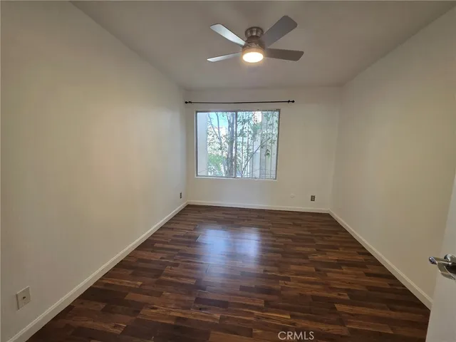 an empty room with wooden floor chandelier fan and windows