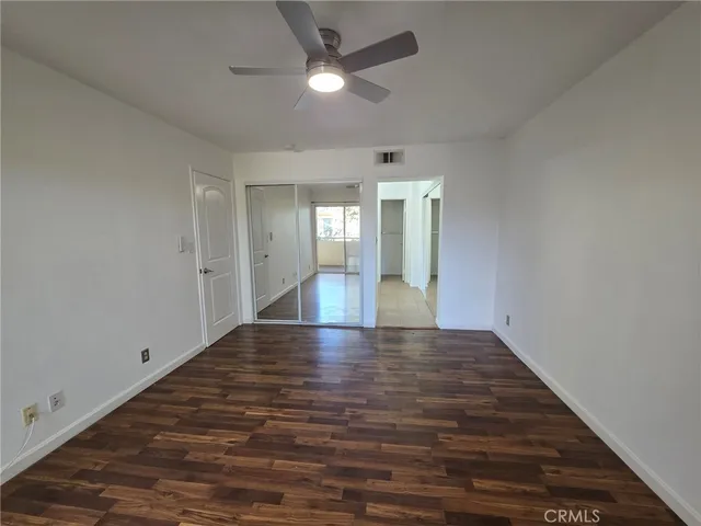 a view of empty room with wooden floor and fan
