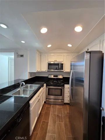 a kitchen with kitchen island granite countertop a sink stainless steel appliances and cabinets