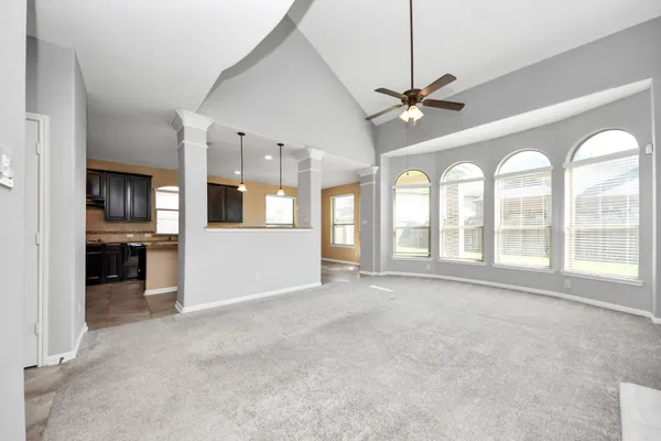 a view of an empty room with a window and kitchen view