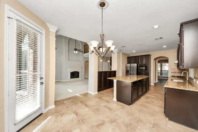 a view of a kitchen with kitchen island a large counter top space a sink stainless steel appliances and cabinets