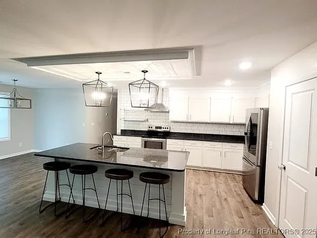 a kitchen with stainless steel appliances kitchen island a table chairs in it and wooden floors