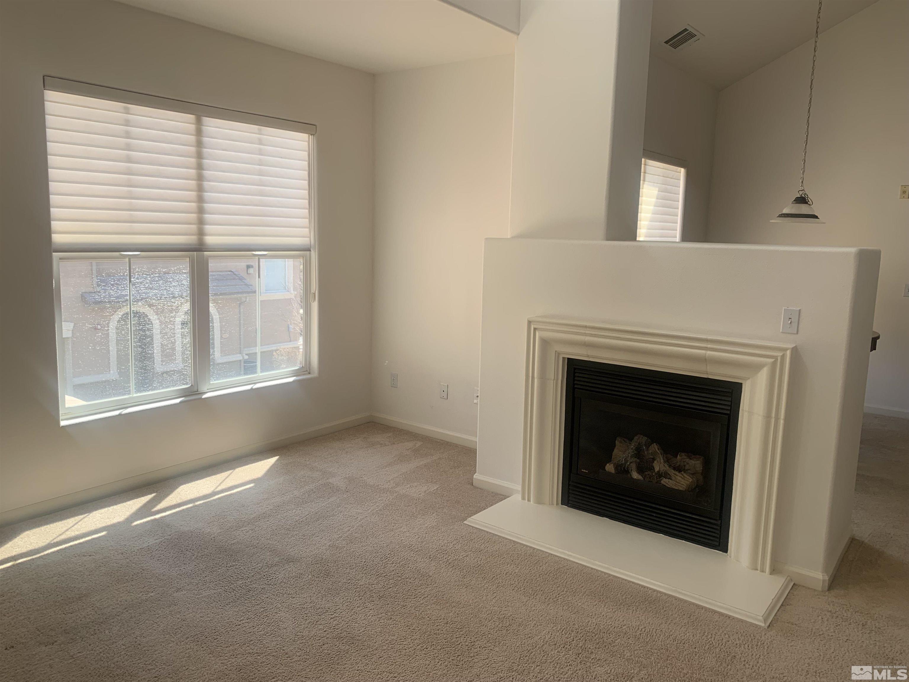 1325 South Meadows Parkway, Unit 422 Reno, NV 89521 - Photo 3 of 10 a living room with a fireplace and a window