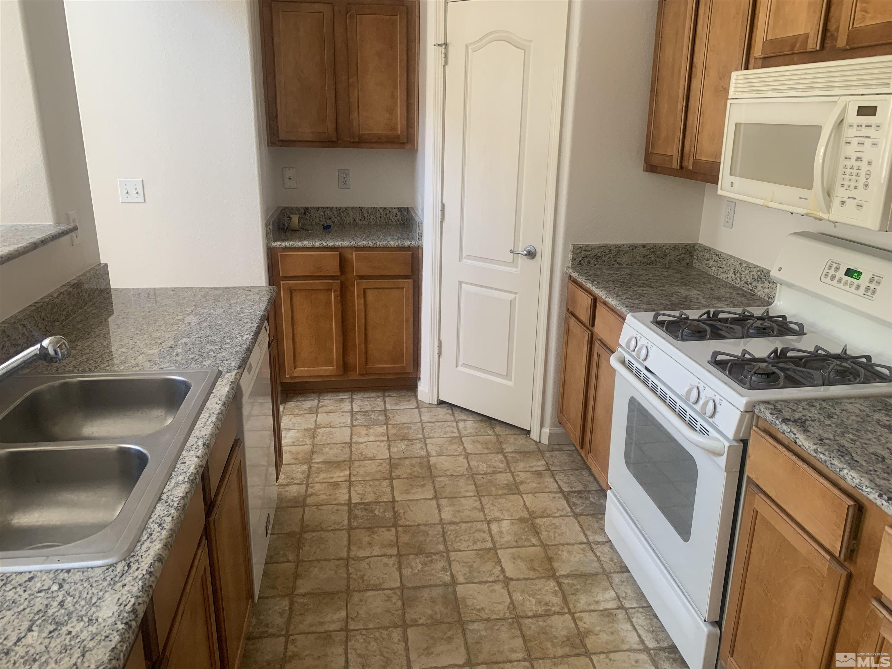 1325 South Meadows Parkway, Unit 422 Reno, NV 89521 - Photo 5 of 10 a kitchen with granite countertop a stove sink and cabinets
