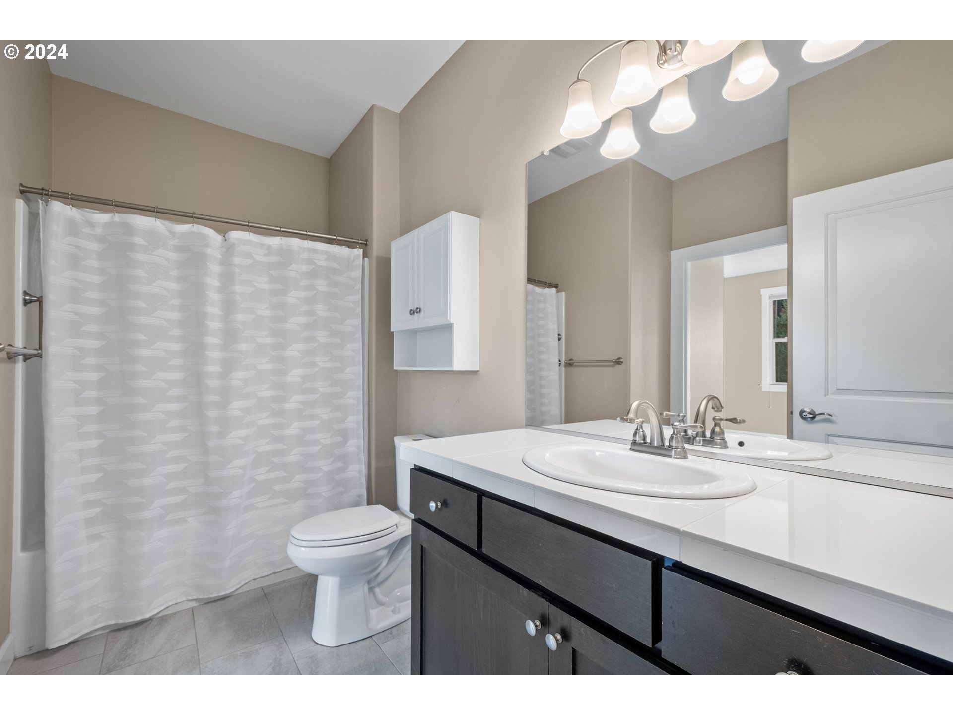 17632 Northeast 17th Avenue Ridgefield, WA 98642 - Photo 21 of 30 a bathroom with a sink a toilet a mirror a lamp and shower curtain