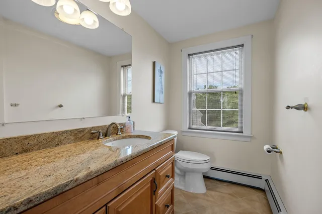 a bathroom with a granite countertop sink a toilet and a window