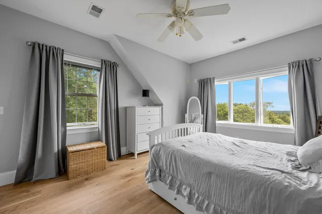 a bedroom with a bed next to a large window with wooden floor