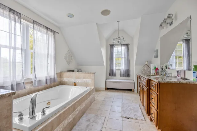 a spacious bathroom with a tub sink and mirror